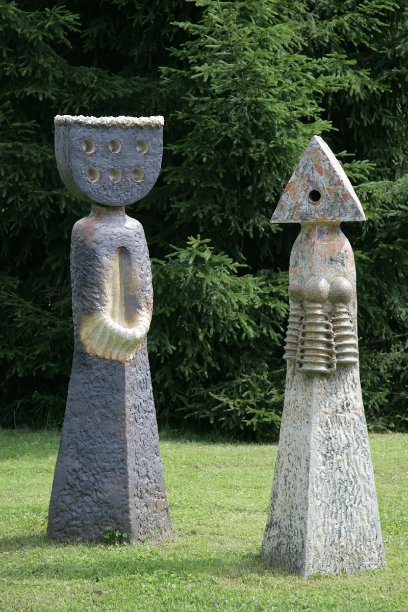 Dvojice šedých figur, jedna s korunou, druhá s trojúhelníkovou hlavou