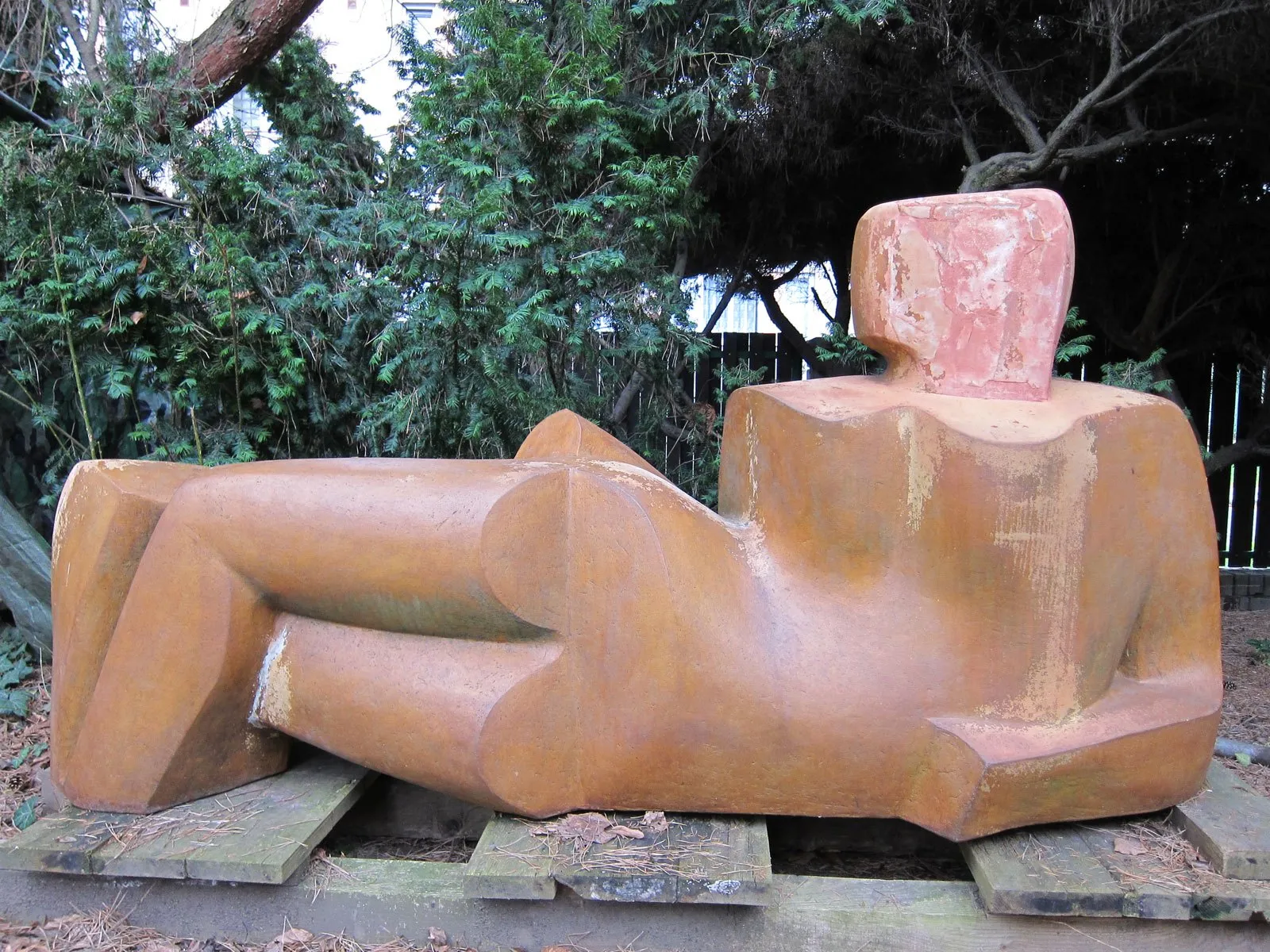 Ležící figura s cihlově červeným povrchem venku