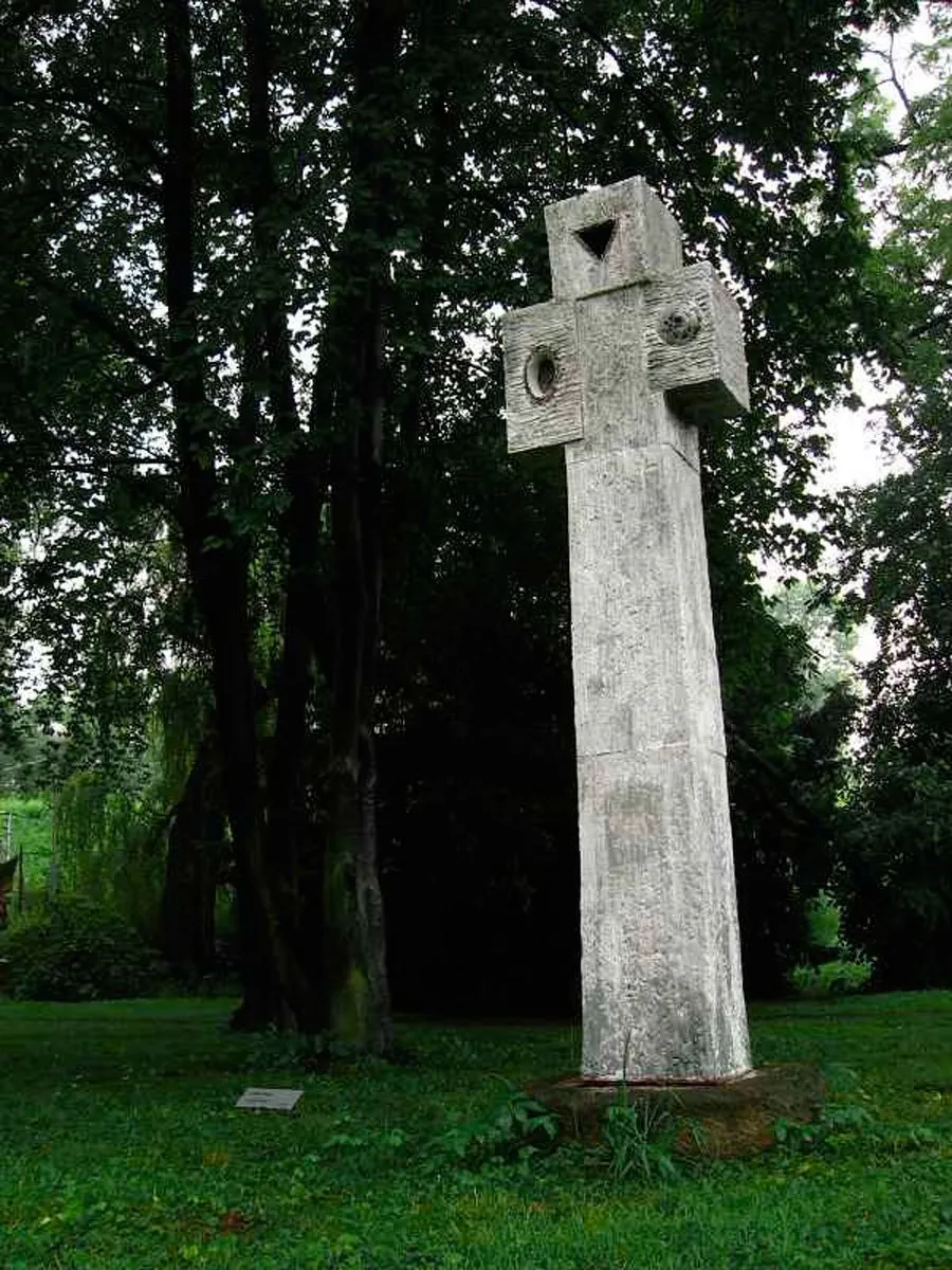 Vysoký světlý kříž s kruhovými otvory v parku